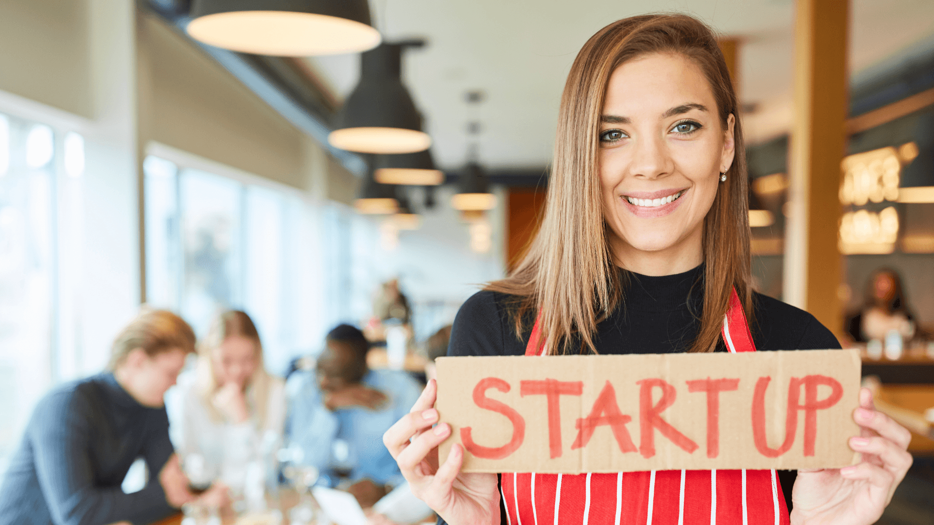 Gründerin hält ein Pappschild mit der Aufschrift Startup